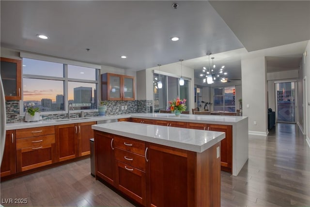 kitchen featuring decorative light fixtures, tasteful backsplash, a kitchen island, sink, and dark wood-type flooring