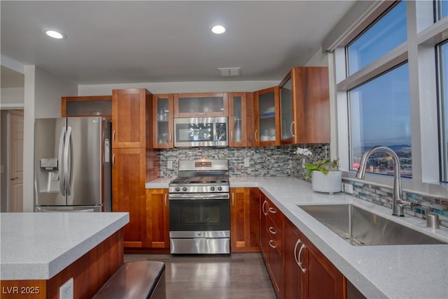 kitchen with backsplash, dark hardwood / wood-style floors, sink, light stone countertops, and appliances with stainless steel finishes