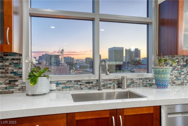 kitchen featuring decorative backsplash, sink, dishwasher, and light stone countertops