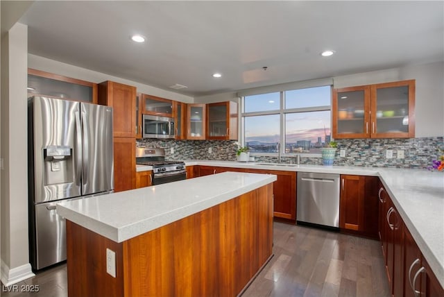 kitchen with appliances with stainless steel finishes, tasteful backsplash, a center island, dark hardwood / wood-style flooring, and sink