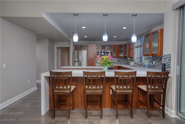 kitchen with tasteful backsplash, kitchen peninsula, sink, hanging light fixtures, and stainless steel appliances