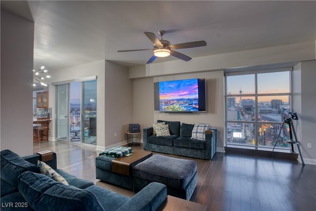 living room featuring a wealth of natural light, ceiling fan with notable chandelier, and dark hardwood / wood-style floors