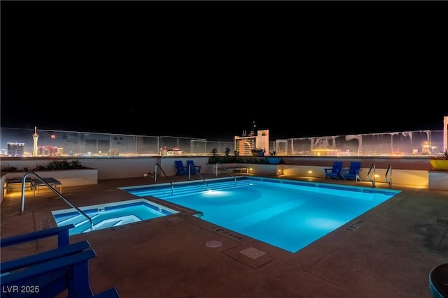 pool at night featuring a community hot tub and a patio