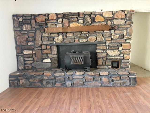 room details featuring a stone fireplace, a wood stove, and hardwood / wood-style flooring