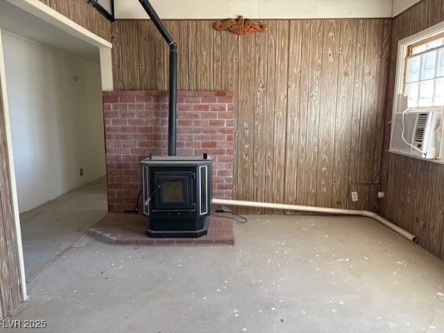 unfurnished living room featuring cooling unit, wooden walls, and a wood stove