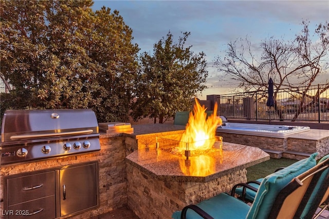 patio terrace at dusk featuring a fire pit, grilling area, and area for grilling