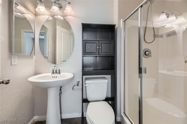 bathroom featuring toilet, a shower with door, and sink