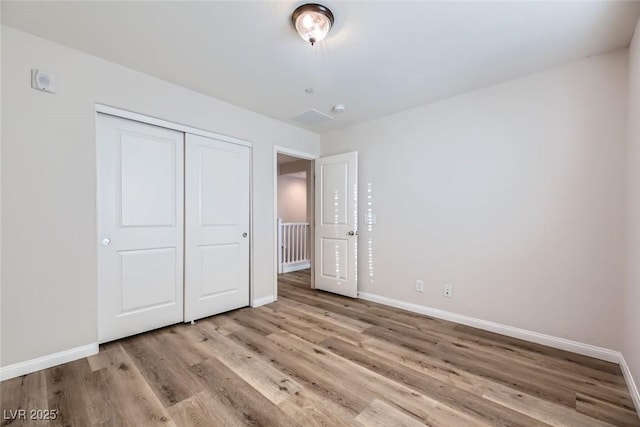 unfurnished bedroom with a closet and light wood-type flooring