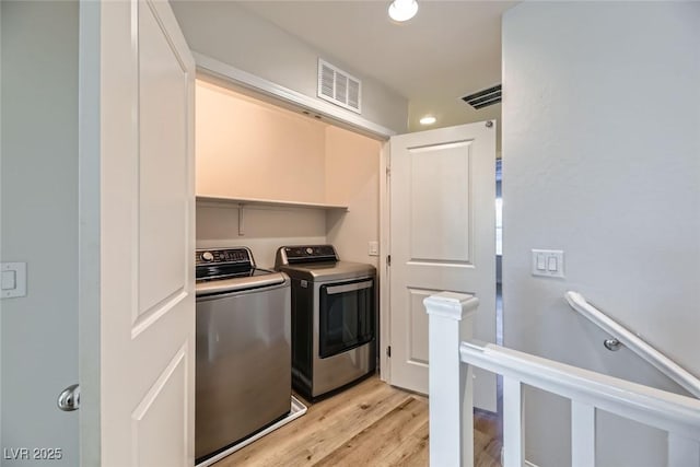 laundry room with independent washer and dryer and light hardwood / wood-style flooring