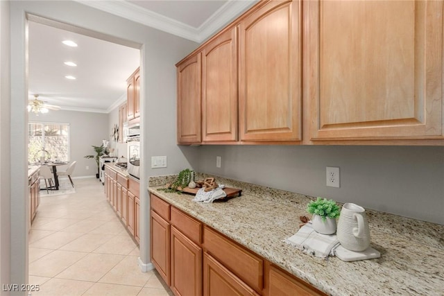 kitchen with light stone countertops, ornamental molding, oven, ceiling fan, and light tile patterned floors