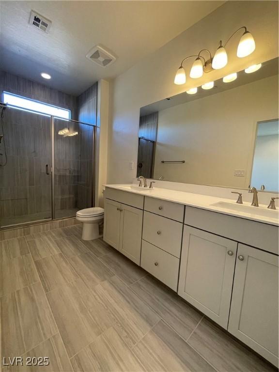 bathroom featuring toilet, a shower with shower door, and vanity