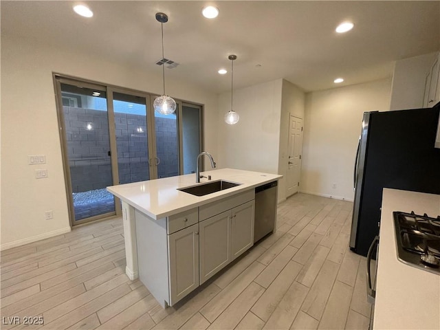 kitchen with gray cabinets, sink, hanging light fixtures, a kitchen island with sink, and appliances with stainless steel finishes