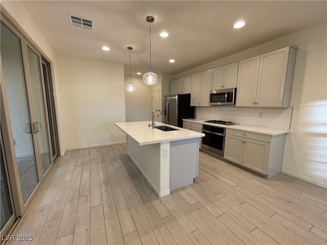 kitchen featuring sink, hanging light fixtures, appliances with stainless steel finishes, and light wood-type flooring