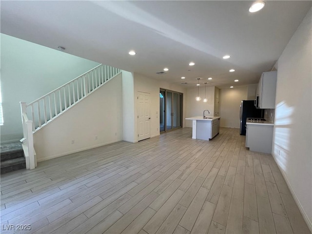 unfurnished living room with sink and light hardwood / wood-style floors