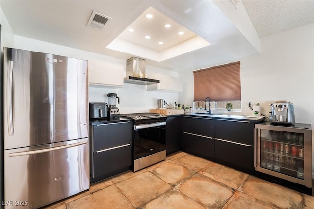 kitchen with wine cooler, sink, white cabinetry, appliances with stainless steel finishes, and wall chimney exhaust hood