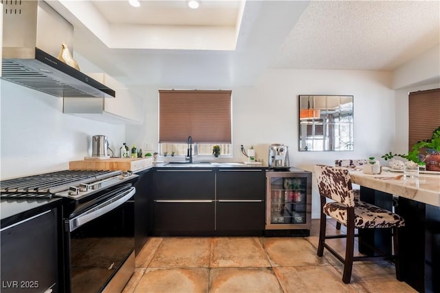 kitchen featuring island range hood, gas stove, wine cooler, a textured ceiling, and sink