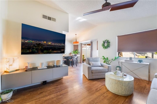 living room featuring a textured ceiling, ceiling fan, vaulted ceiling, and hardwood / wood-style flooring