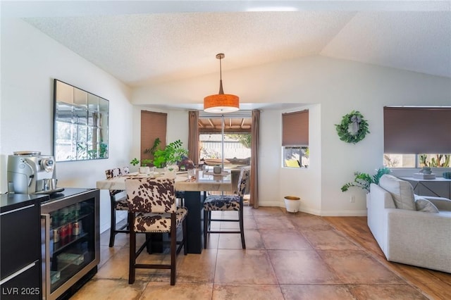 dining room featuring a textured ceiling, beverage cooler, and vaulted ceiling