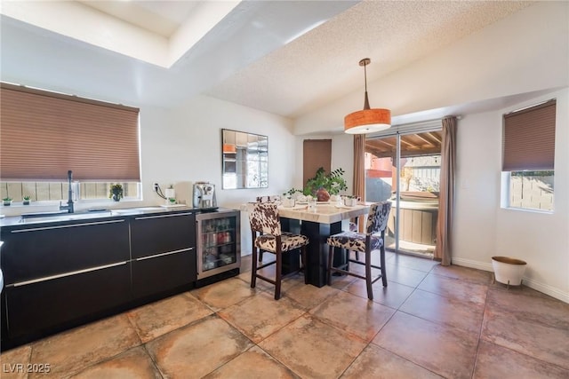 dining space featuring a textured ceiling, vaulted ceiling, wine cooler, and sink