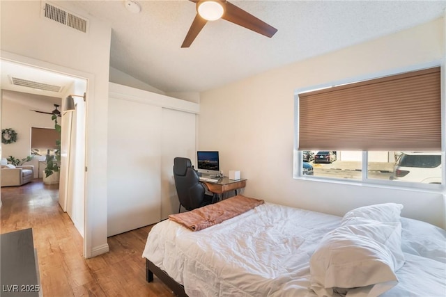 bedroom with light wood-type flooring, ceiling fan, vaulted ceiling, and a closet