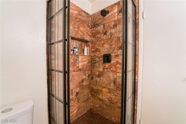 bathroom featuring toilet and a tile shower