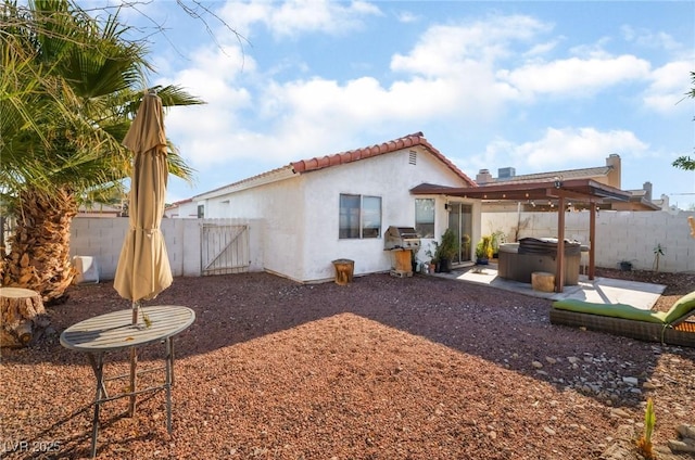 rear view of house featuring a hot tub and a patio