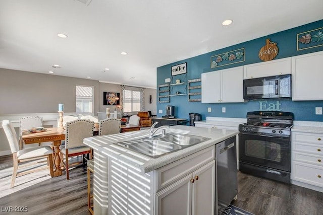 kitchen featuring sink, white cabinetry, black appliances, and a kitchen island with sink