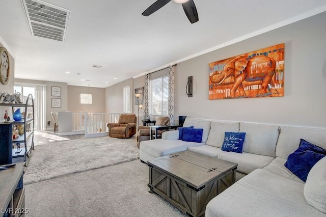 carpeted living room with ceiling fan and crown molding