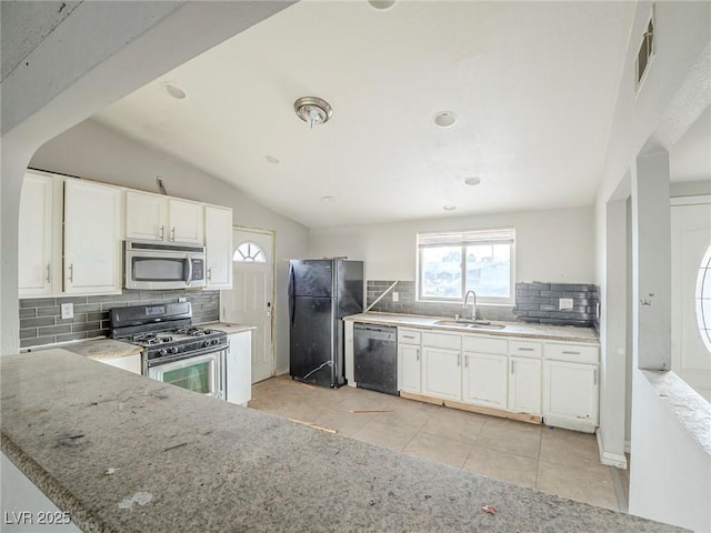 kitchen with vaulted ceiling, black appliances, sink, white cabinetry, and light tile patterned floors