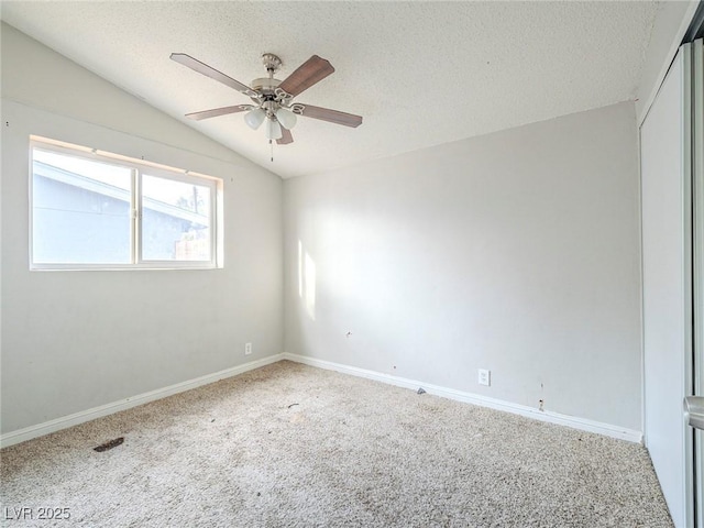 carpeted spare room featuring ceiling fan, vaulted ceiling, and a textured ceiling