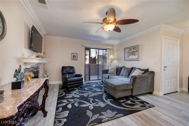 living room featuring ceiling fan, ornamental molding, and light hardwood / wood-style flooring