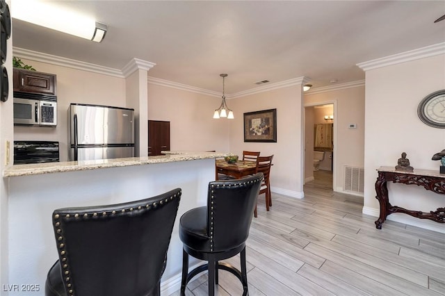 kitchen with light hardwood / wood-style floors, appliances with stainless steel finishes, a chandelier, ornamental molding, and pendant lighting