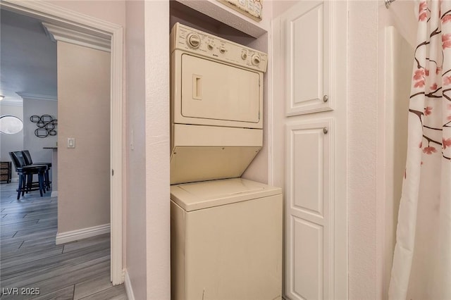 washroom with light hardwood / wood-style floors, crown molding, and stacked washer and dryer