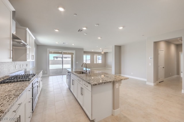 kitchen featuring white cabinets, appliances with stainless steel finishes, sink, ceiling fan, and a center island with sink