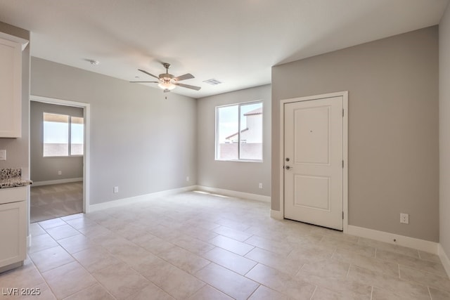 tiled spare room featuring ceiling fan