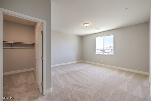 unfurnished bedroom featuring a spacious closet, light colored carpet, and a closet