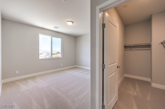 unfurnished bedroom with a spacious closet, carpet, and a closet