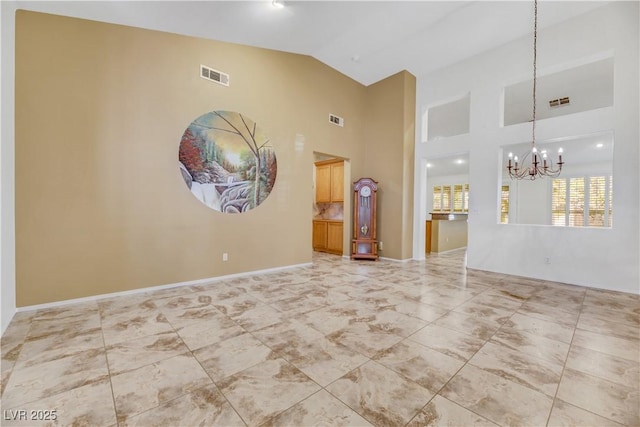 empty room with high vaulted ceiling and an inviting chandelier