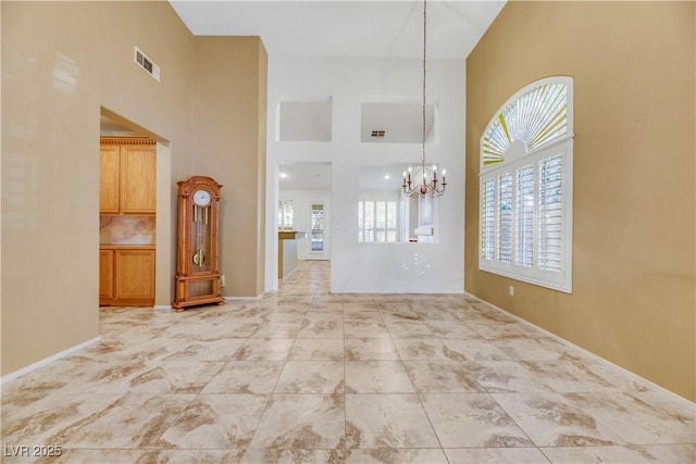 unfurnished living room with an inviting chandelier and a high ceiling