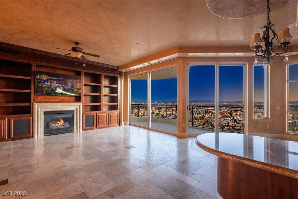 unfurnished living room featuring built in features and ceiling fan with notable chandelier