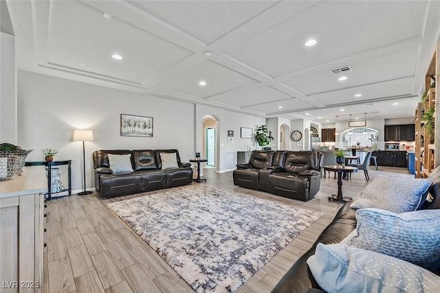 living room with beam ceiling, coffered ceiling, and light hardwood / wood-style floors