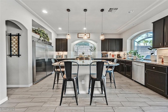 kitchen with hanging light fixtures, a barn door, appliances with stainless steel finishes, and dark brown cabinets