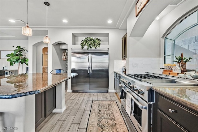 kitchen featuring decorative light fixtures, a center island, dark stone counters, and high quality appliances