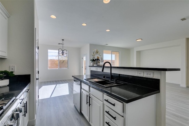 kitchen with appliances with stainless steel finishes, an island with sink, white cabinetry, and sink