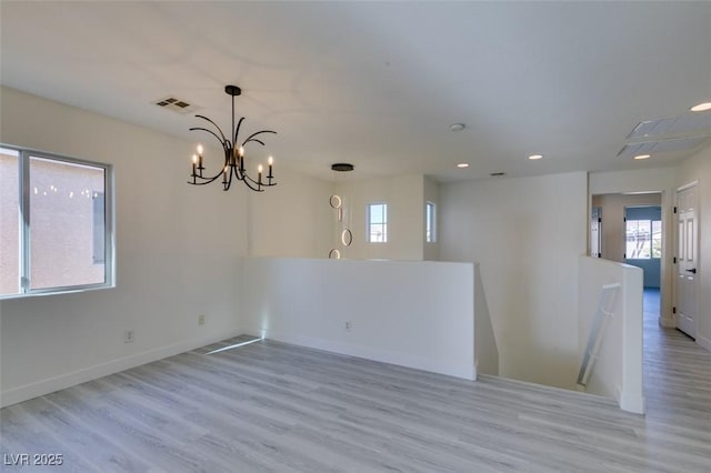 spare room featuring light wood-type flooring and an inviting chandelier