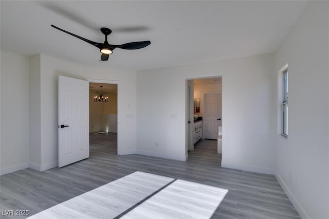 unfurnished bedroom featuring ceiling fan with notable chandelier and hardwood / wood-style floors