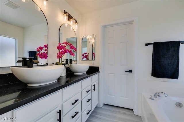 bathroom featuring wood-type flooring, vanity, and a washtub