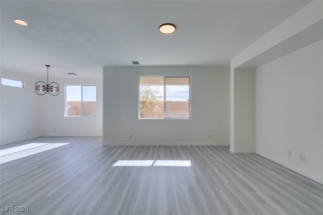 spare room with light hardwood / wood-style flooring and a chandelier