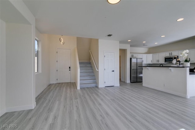 kitchen with stainless steel appliances, light hardwood / wood-style floors, and white cabinetry