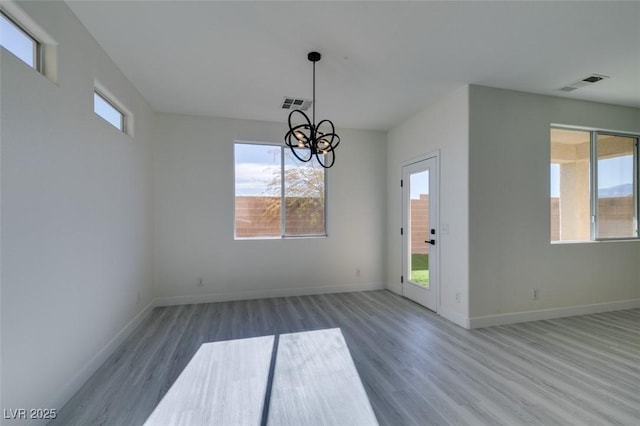 unfurnished dining area featuring hardwood / wood-style flooring and a notable chandelier